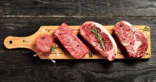 Fresh raw Prime Black Angus beef steaks on wooden board